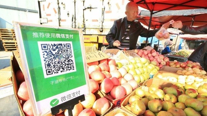Một người bán quả tại Đại Liên nhận thanh toán bằng mã QR. Ảnh: Nikkei